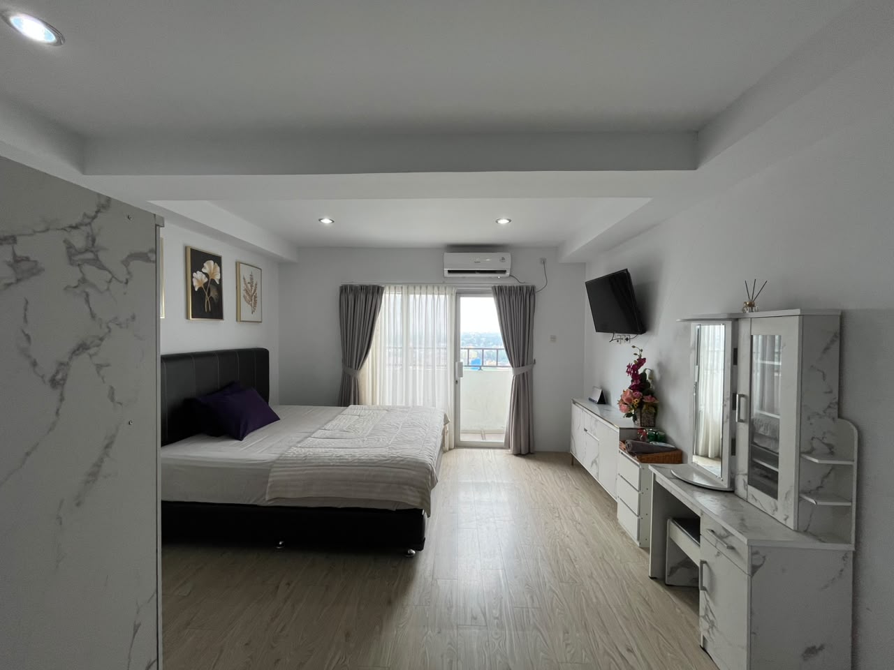 Unit Deluxe GUMIR Haven bernuansa putih dengan tempat tidur, TV dan meja rias marmer