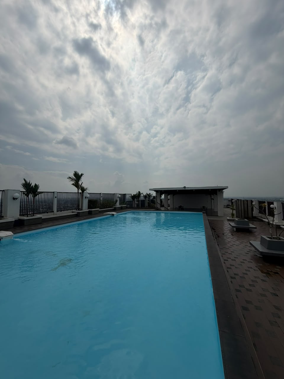 Kolam renang rooftop GUMIR Haven dengan pemandangan langit sore